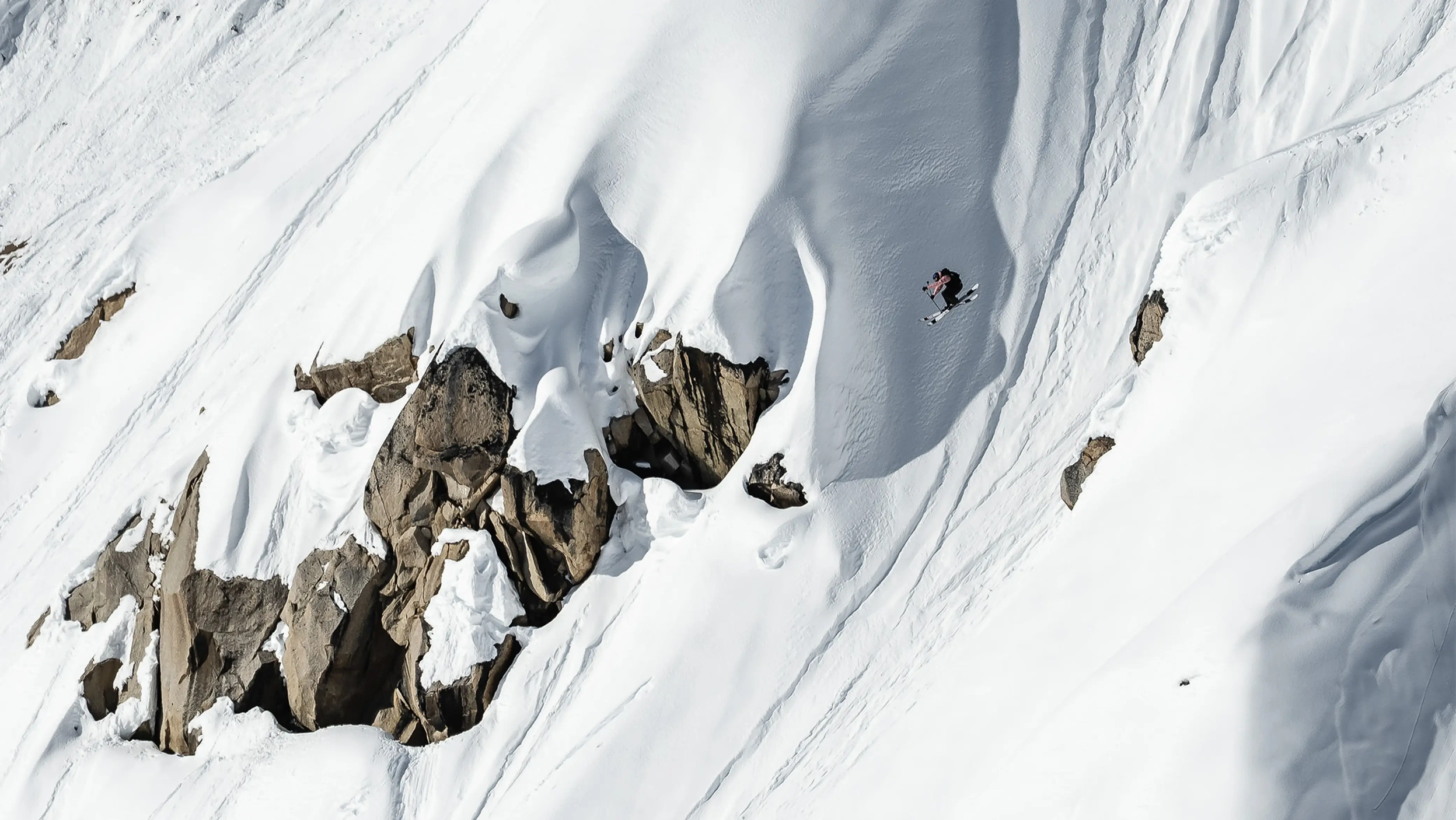 Лыжник в полете после большого дропа в горах