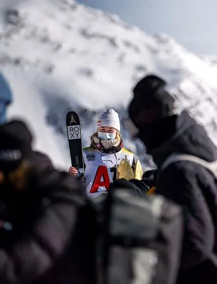 Фотографы фотографируют спортсменку в экипировке и с лыжами компании ATOMIC.