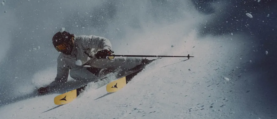 Ски-альпинист спускается с гор на лыжах и в экипировке компании ATOMIC.