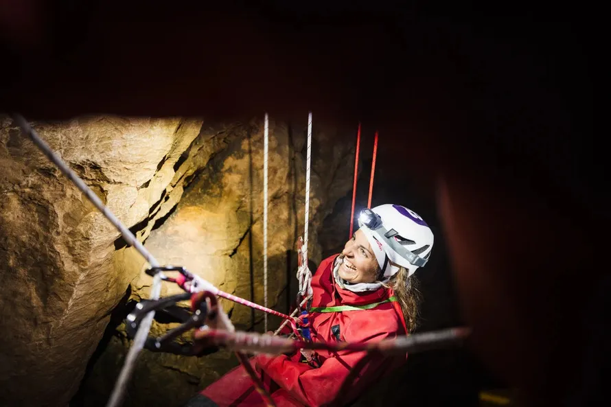 Девушка на страховочных веревках и в шлеме компании Beal.