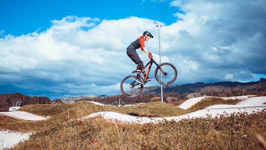 Девушка делает прыжок на велосипеде.