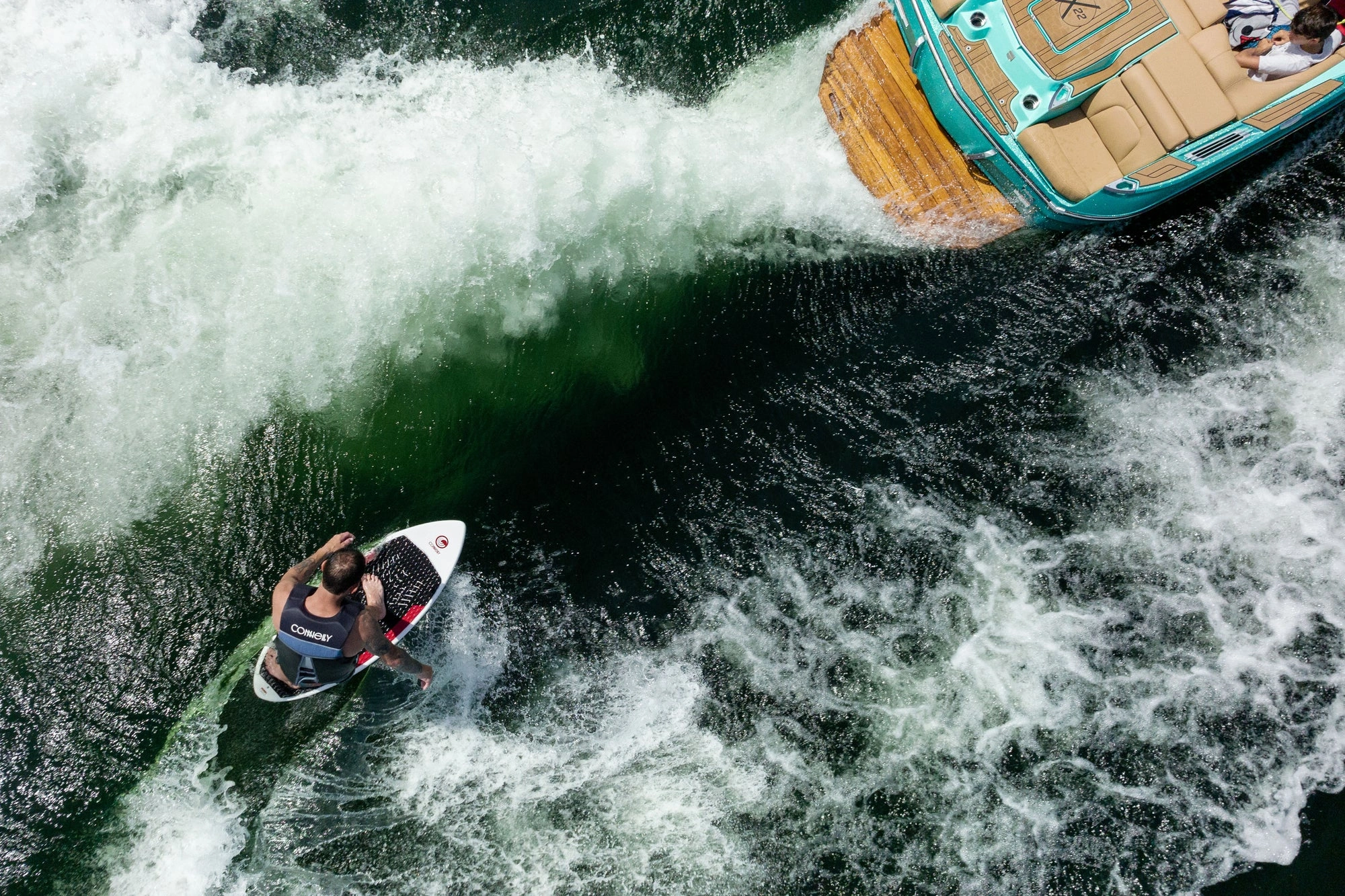 мужчина скользит на вейксерфе по волне за катером