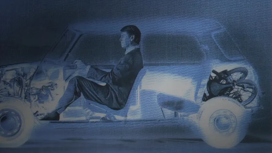 Разрез автомобиля, в котором сидит мужчина, а в багажнике лежит велосипед.