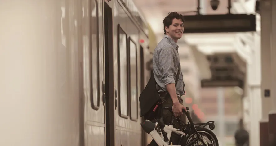 Мужчина держит складной велосипед компании DAHON.