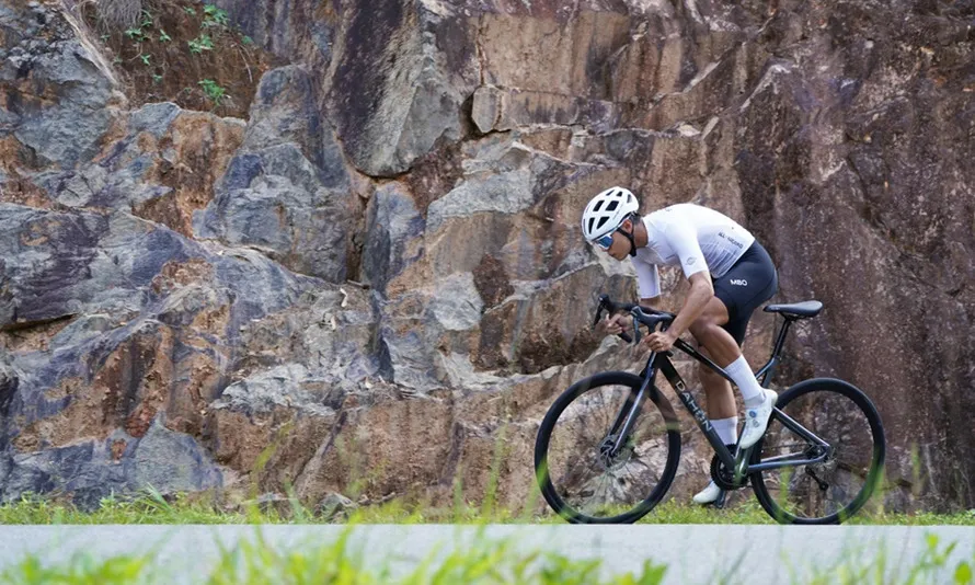 Велосипедист едет по дороге на велосипеде компании DAHON.