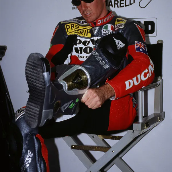 Спортсмен одевает ботинки с металлическими слайдерами компании DAINESE