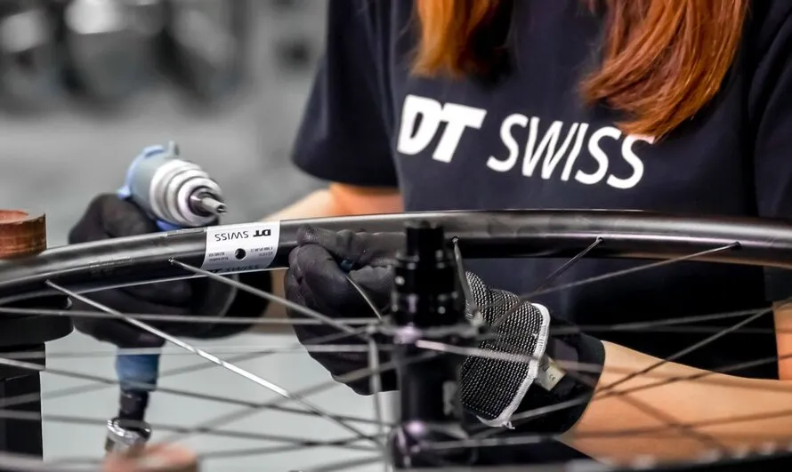 Рабочая компании DT SWISS за сборкой колеса со спицами.