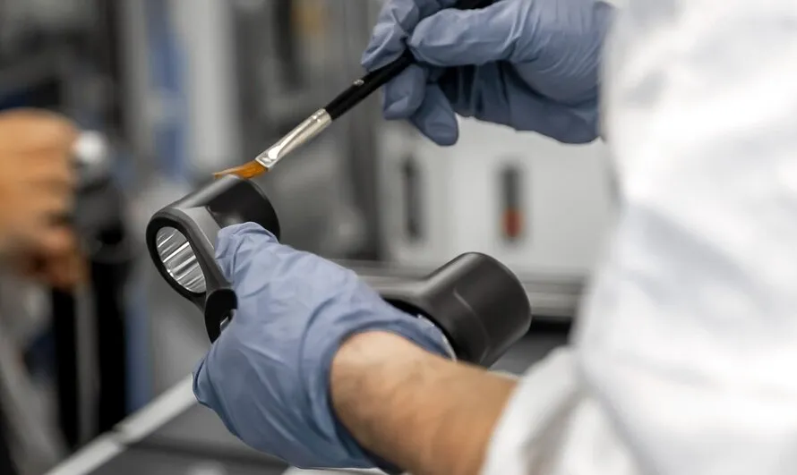 Рабочий компании DT SWISS смазывает кисточкой велосипедный компонент производства DT SWISS.