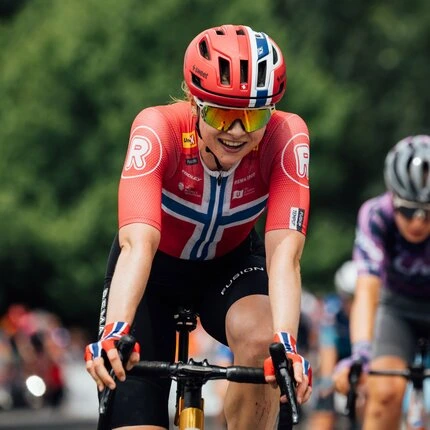 Велосипедистка едет улыбаясь на велосипеде.