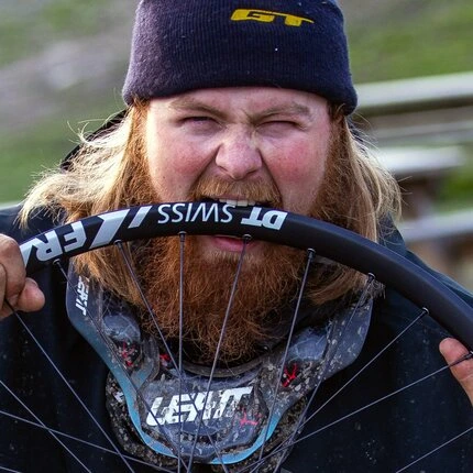 Мужчина кусает обод колеса производства DT SWISS.