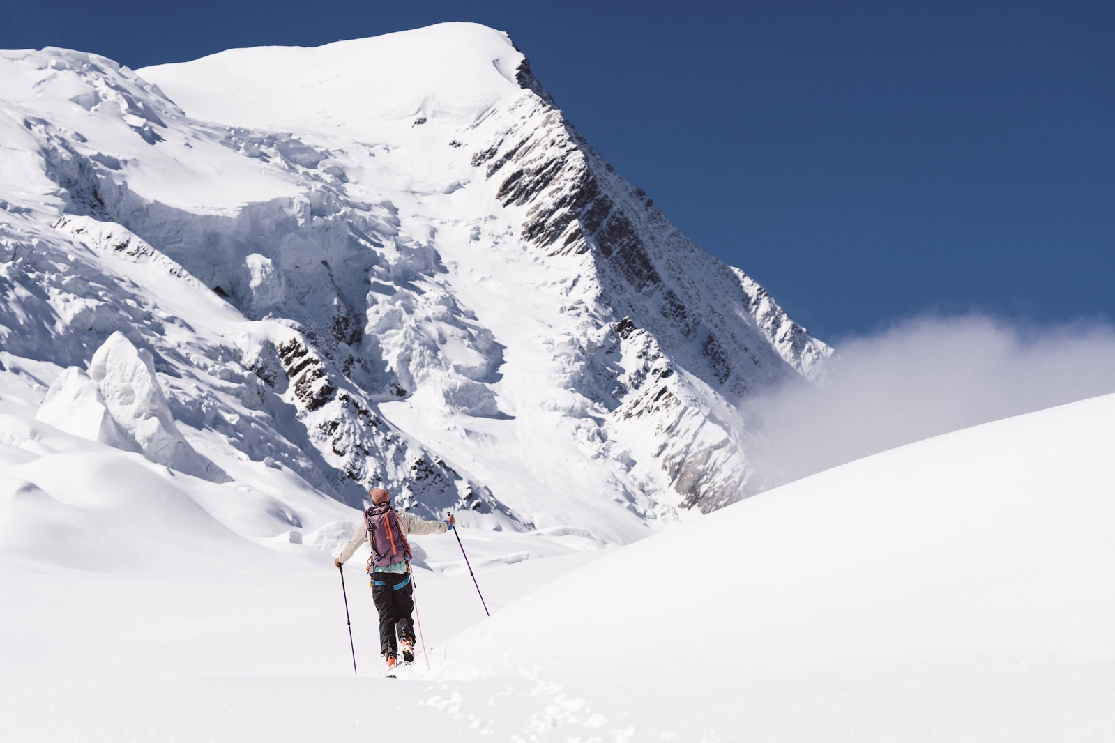 женщина поднимается к заснеженной горной вершине