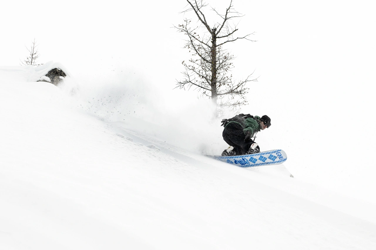 Райдер Forest Bailey на сноуборде Gnu в глубоком снегу 