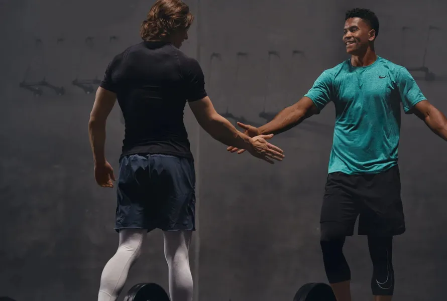 Двое мужчин в тренажерном зале приветствуют друг друга.