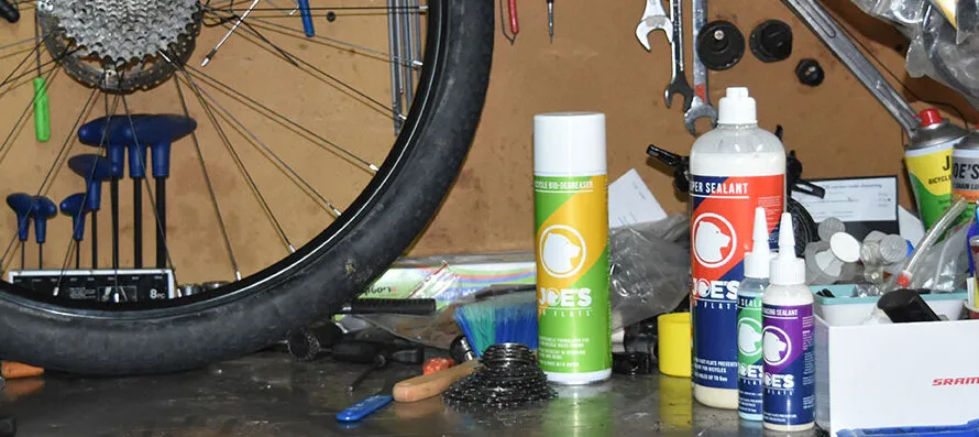 Продукция бренда JOE'S на столе вместе со снятым велосипедным колесом.