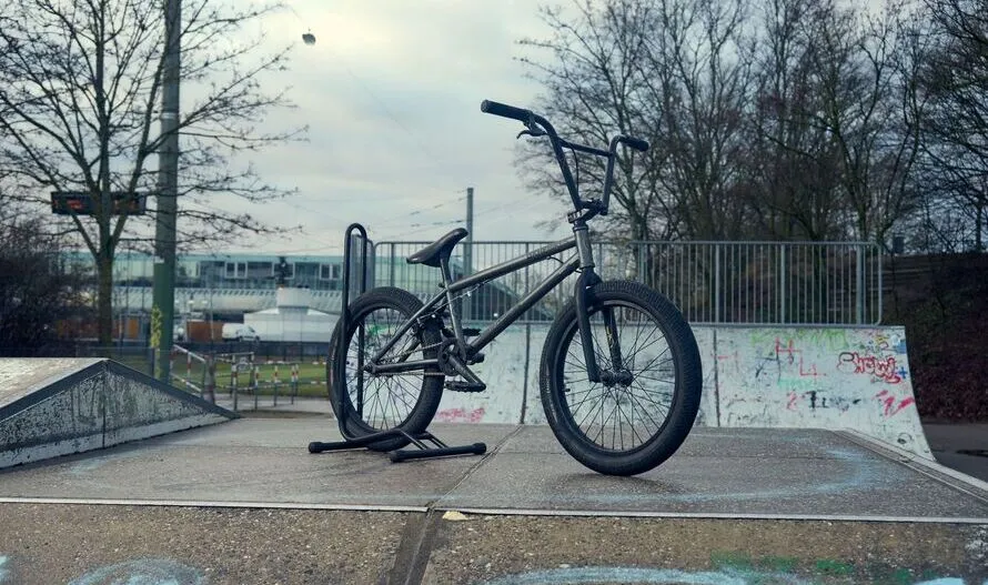 Велосипед BMX производства компании KHEBIKES стоит на стойке под заднее колесо.