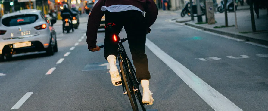 Велосипедист едет по улице на велосипеде с установленным сзади фонариком компании KNOG.