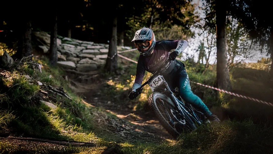 Велосипедист спускается по лесной трассе на велосипеде.