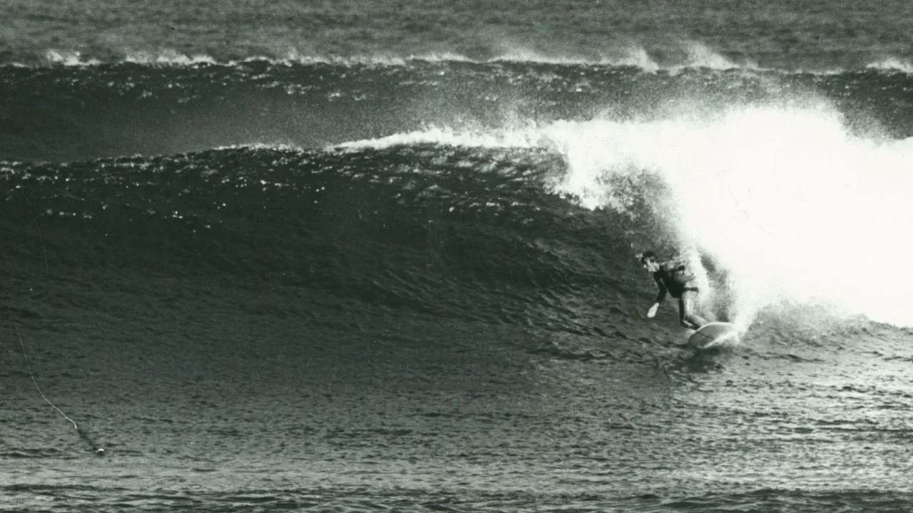 Черно-белый снимок человека, занимающегося серфингом.