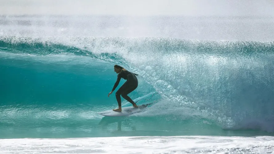 Девушка занимается серфингом в экипировке Rip Curl.