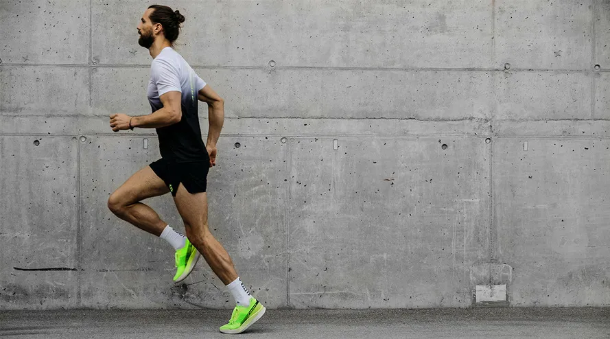 Спортсмен бежит в кроссовках с динамичной карбоновой пластиной компании SCOTT.