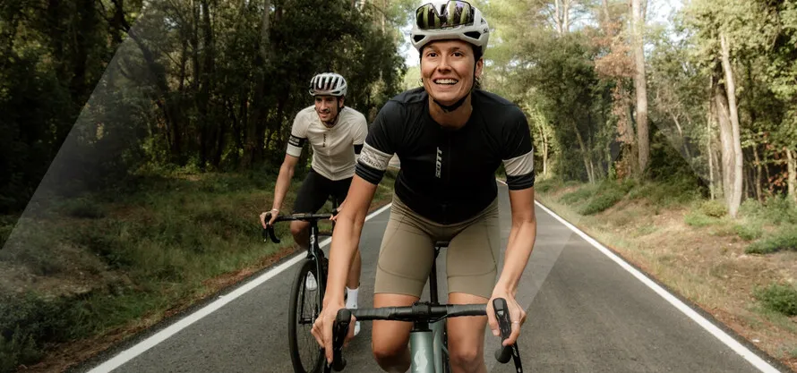 Женщина и мужчина едут по дороге в экипировке и на велосипедах компании SCOTT.