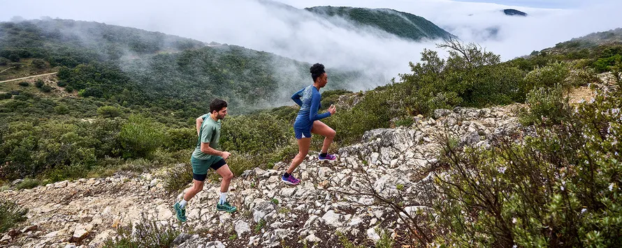 Мужчина и женщина бегут по горной дороге в экипировке компании SCOTT.