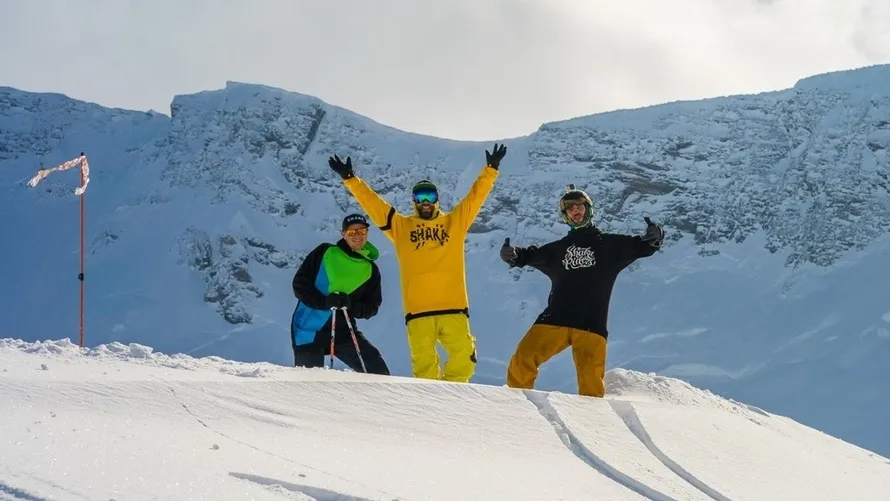 Трое мужчин на снежном склоне а одежде производства бренда SHAKA.