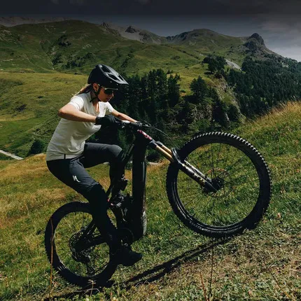 Девушка заезжает на лесную горку на велосипеде производства компании Specialized.