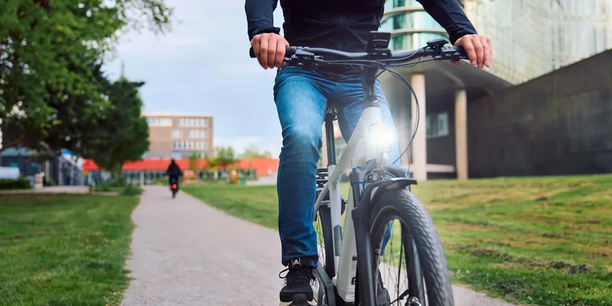 Велосипедист едет на велосипеде с включенным передним фонарем компании TRELOCK