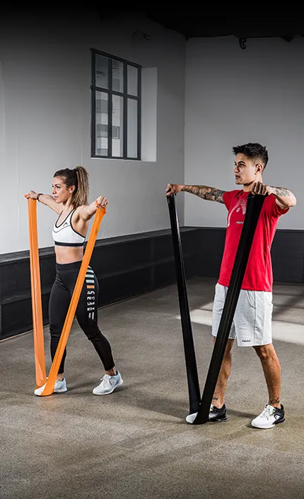 Мужчина и женщина занимаются в спортивном зале, используя экипировку и продукцию бренда HEAD.