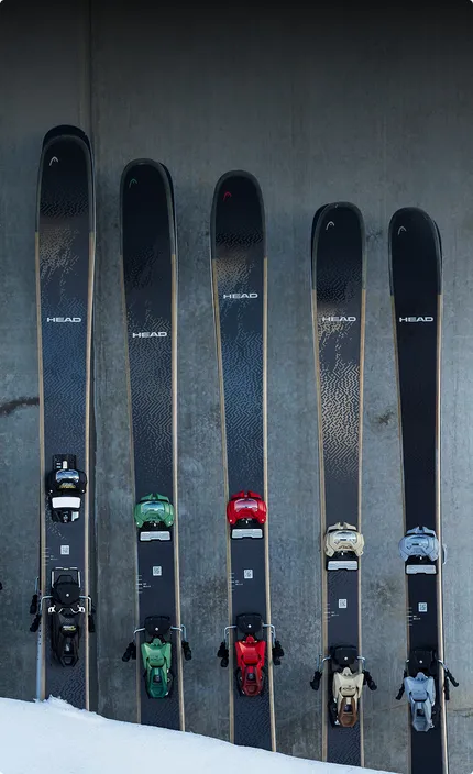 Пять пар горных лыж бренда HEAD с креплениями компании TYROLIA, воткнутые в сугроб.