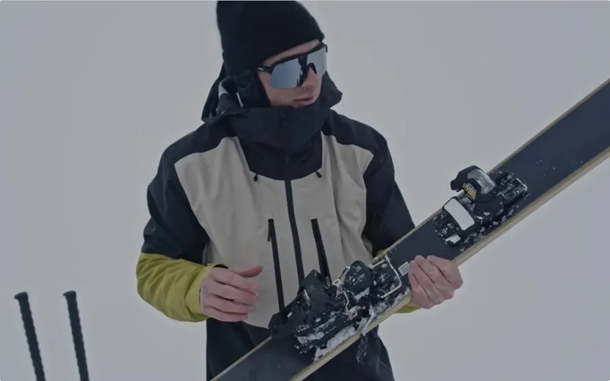 Мужчина смотрит на горные лыжи с креплениями производства компании TYROLIA.