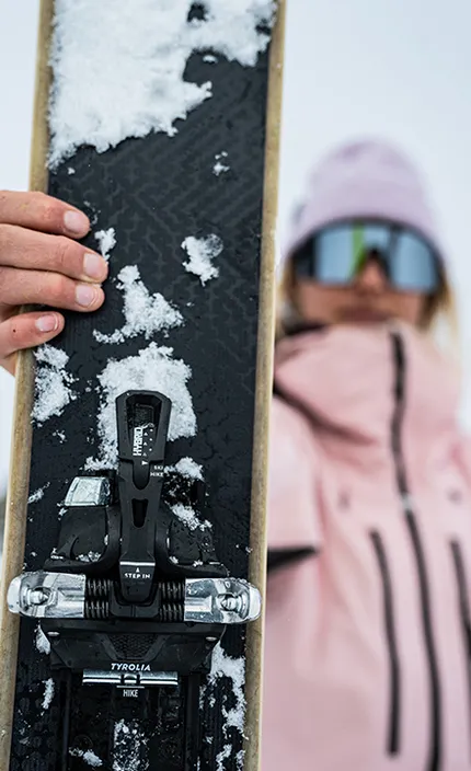 Девушка демонстрирует горную лыжу бренда HEAD с креплением компании TYROLIA.