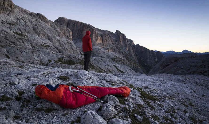 Турист в горах со спальником и треккинговыми палками компаниии VIPOLE.